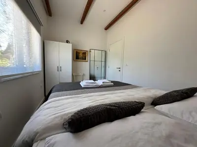 a white bedroom with two beds and a window at Small House Apartment in Bihać
