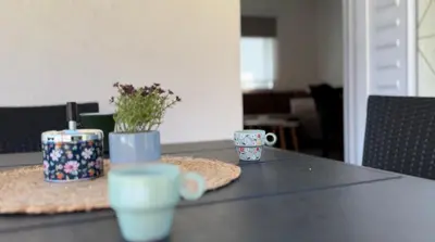 a table with two cups and flowers on it at Small House Apartment in Bihać