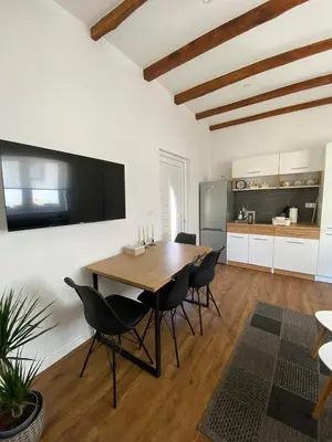 a dining room with a table and chairs and a kitchen at Small House Apartment in Bihać