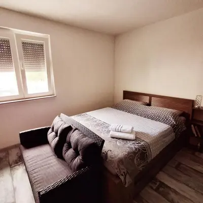 a bedroom with a bed and two windows at Peace Holiday Home in Bihać