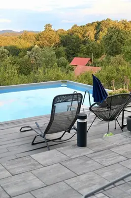 two chairs and an umbrella next to a swimming pool at Casa Rado in Banja Luka