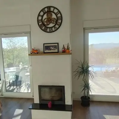 a living room with a fireplace and a clock on the wall at Casa Rado in Banja Luka