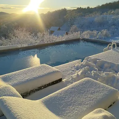 a hot tub covered in snow with the sun in the background at Casa Rado in Banja Luka