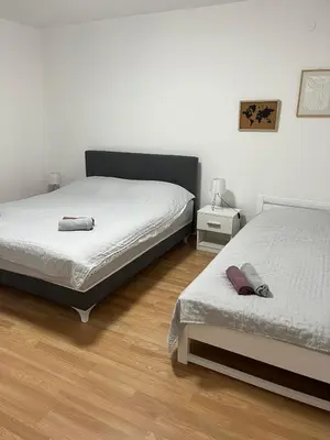 a bedroom with two beds and a wooden floor at Apartman KUNA in Drvar