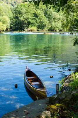 a small boat sitting in the middle of a lake at Riverside Cabin Pisak in Kulen Vakuf
