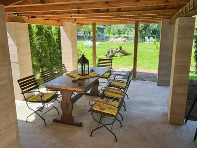 a patio with a wooden table and chairs at Riverside Cabin Pisak in Kulen Vakuf