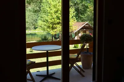 a view from a door of a balcony with a table at Riverside Cabin Pisak in Kulen Vakuf