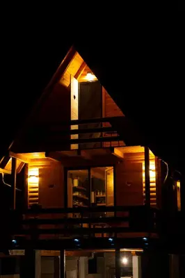 a night view of a house with a balcony at Riverside Cabin Pisak in Kulen Vakuf