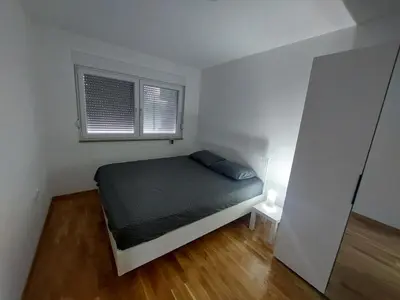 a small bedroom with a bed and two windows at KEJ LUX Apartman in Bosanska Gradiška