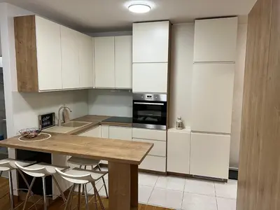 a kitchen with white cabinets and a wooden table at Apartman 23 Lux in Banja Luka
