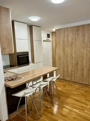 a kitchen with a wooden table and white chairs at Apartman 23 Lux in Banja Luka