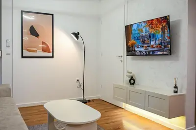 a white living room with a table and a lamp at Apartmani Galerija in Banja Luka