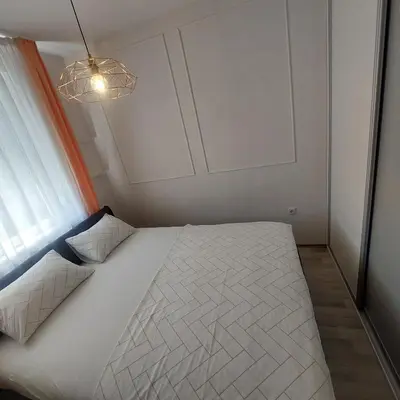 a small bedroom with a white bed with a chandelier at Stan na dan centar Jevrejska Banja Luka in Banja Luka