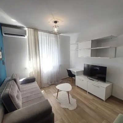 a living room with a couch and a tv and a desk at Stan na dan centar Jevrejska Banja Luka in Banja Luka