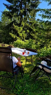 a man sitting at a table in a chair next to a picnic table at Apartmani Viktory in Šišava