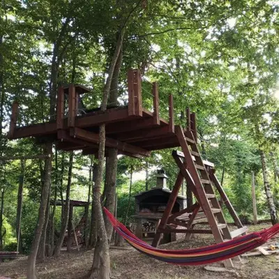 a tree house with a hammock in a forest at Vikendica Novska planina in Rudice