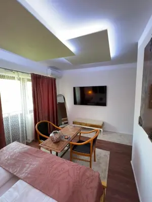 a living room with a table and chairs and a tv at Soba sa kupaonom i balkonom Aman in Bihać