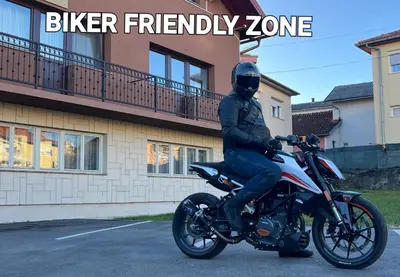 a man sitting on a motorcycle in a parking lot at Soba sa kupaonom i balkonom Aman in Bihać
