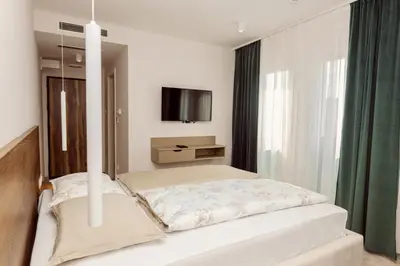 a bedroom with a bed and a tv on the wall at Hotel Marina Home in Prijedor