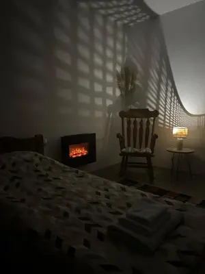 a bedroom with a bed and a chair and a fireplace at EFESA Apartments in Visoko