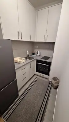 a kitchen with white cabinets and a black appliance at Stan na dan Banjaluka Ada 3 in Rebrovac