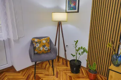 a room with a chair and a lamp and plants at Apartman Toromanovic in Bihać