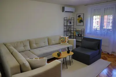 a living room with a white couch and a blue chair at Apartman Toromanovic in Bihać