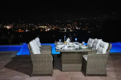 a table and chairs with a view of a city at night at Vikendica-Villa Belvedere Srebrenik in Srebrenik