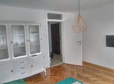 a living room with white cabinets and a wooden floor at Apartman iza Boske in Banja Luka