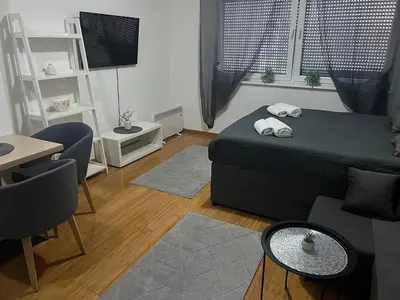 a bedroom with a bed and a table and a desk at Studio apartman MyPLACE in Bihać