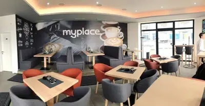 a restaurant with tables and chairs and a sign on the wall at Studio apartman MyPLACE in Bihać