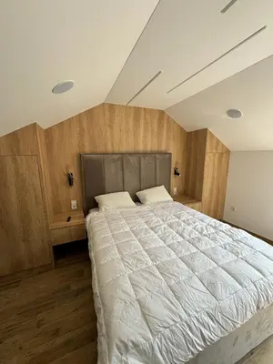 a bedroom with a large white bed with wooden walls at Apartman Dom in Vareš