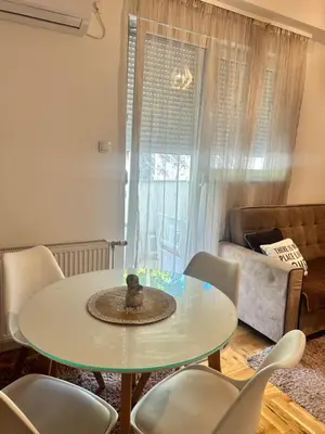a table and chairs in a living room with a window at Apartment Jelena in Banja Luka