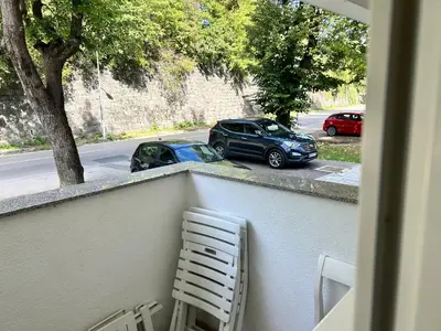 a balcony with a chair and two cars parked on a street at Apartment Jelena in Banja Luka