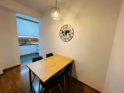 a dining room with a wooden table and a clock on the wall at Apartment Gina-Centar in Banja Luka