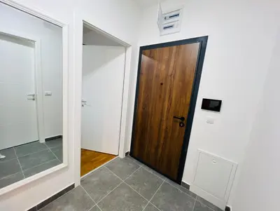 a hallway with a wooden door and a mirror at Apartment Gina-Centar in Banja Luka