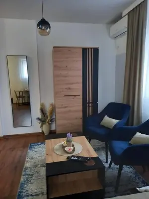 a living room with a table and two blue chairs at Apartman Mijate in Banja Luka