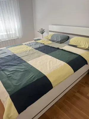 a bed with a colorful blanket on top of it at Apartman SLEEP&JOY Tuzla in Tuzla
