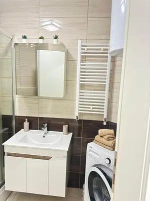 a bathroom with a sink and a washing machine at Apartman SLEEP&JOY Tuzla in Tuzla
