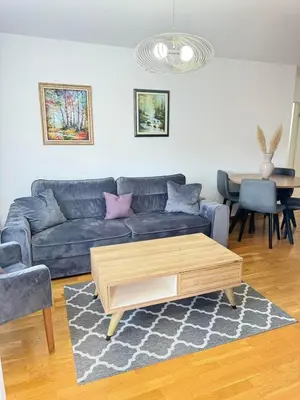a living room with a blue couch and a coffee table at Apartman SLEEP&JOY Tuzla in Tuzla