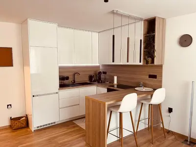 a kitchen with white cabinets and a table and stools at Apartman Alan in Travnik