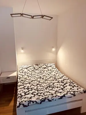 a small bedroom with a bed and a white wall at Apartman Alan in Travnik