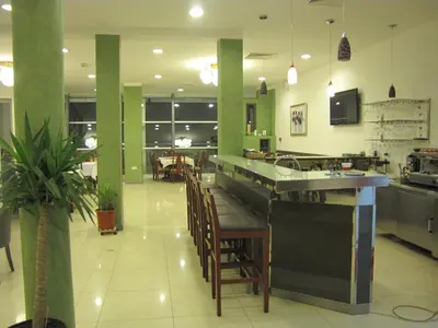 a restaurant with a kitchen with a bar and chairs at Motel Kobilj in Banja Luka