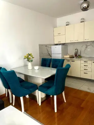 a kitchen with a white table and blue chairs at Apartman 19-Centar in Banja Luka