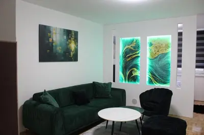 a living room with a green couch and two paintings at Toskana Tuzla in Tuzla