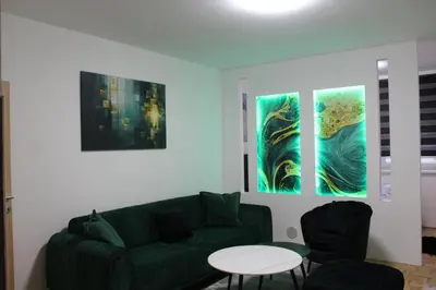 a living room with a green couch and three paintings at Toskana Tuzla in Tuzla