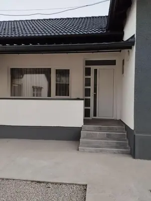 a white house with a door and stairs at Apartman Miloš in Bosanska Dubica