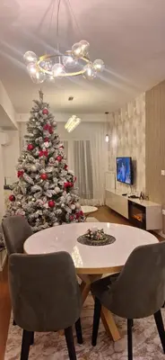 a christmas tree in a living room with a table and chairs at Palata Gold Apartment in Banja Luka