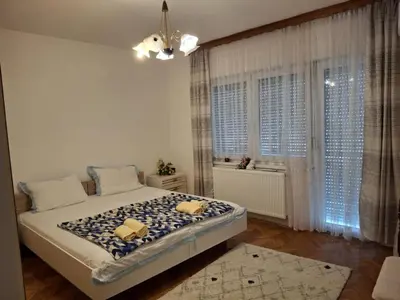 a bedroom with a large bed in a room with windows at Jasmir in Bihać