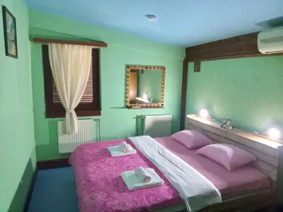 a bedroom with a pink bed and a mirror at Apartman Retro in Žepče